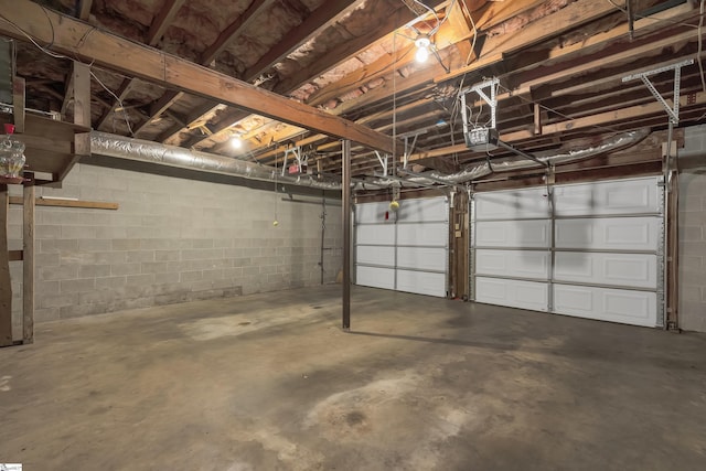 garage featuring concrete block wall and a garage door opener