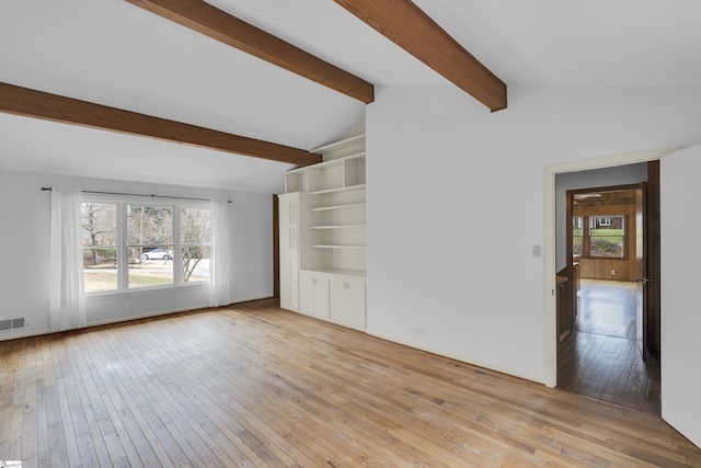 unfurnished living room with lofted ceiling with beams, visible vents, and light wood-style flooring