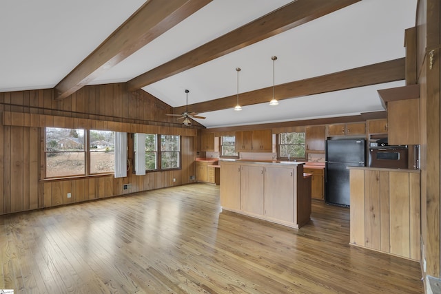 kitchen with wooden walls, a kitchen island, freestanding refrigerator, light countertops, and light wood-type flooring