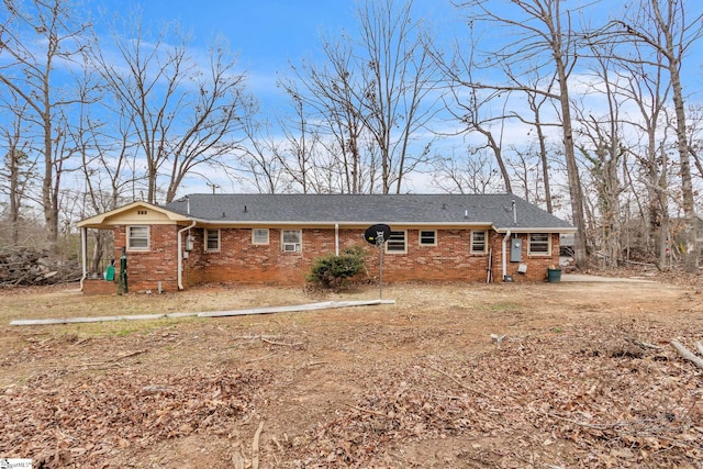 rear view of property featuring a shingled roof and brick siding