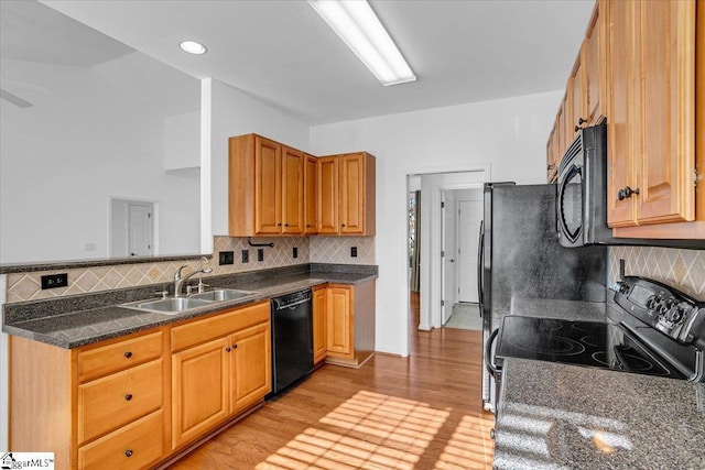 kitchen featuring light wood-style flooring, a sink, decorative backsplash, black appliances, and brown cabinetry