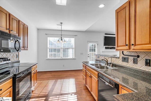 kitchen featuring light wood-style flooring, a sink, black appliances, brown cabinetry, and pendant lighting