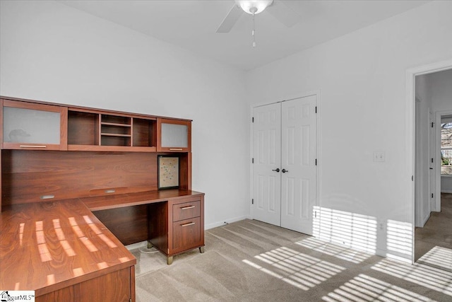 unfurnished office featuring baseboards, a ceiling fan, and light colored carpet