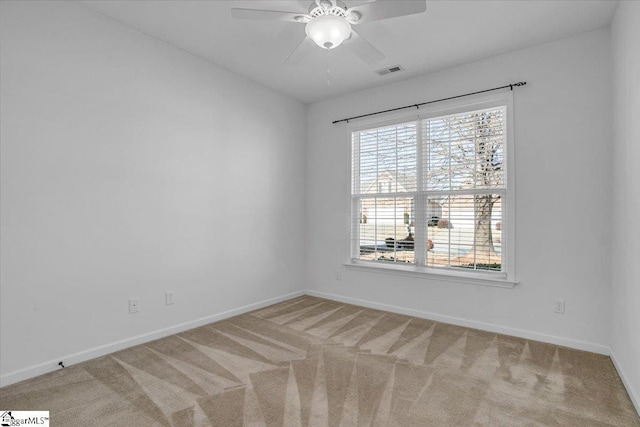 carpeted empty room with visible vents, ceiling fan, and baseboards