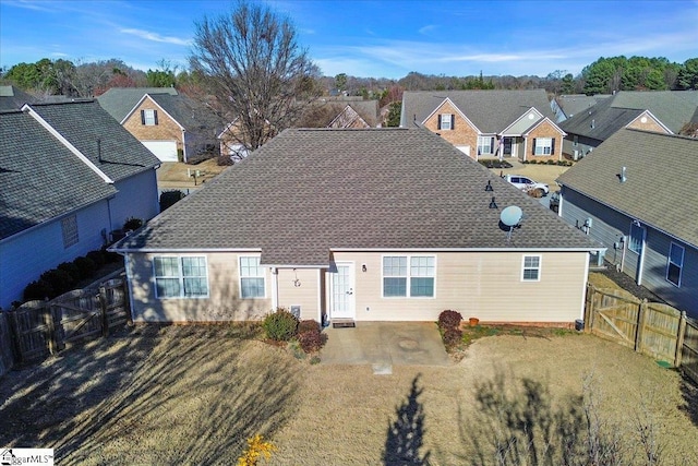 view of front of home with a fenced backyard, a shingled roof, a front yard, a residential view, and a patio area