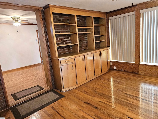 interior space with a ceiling fan, light wood-type flooring, and baseboards