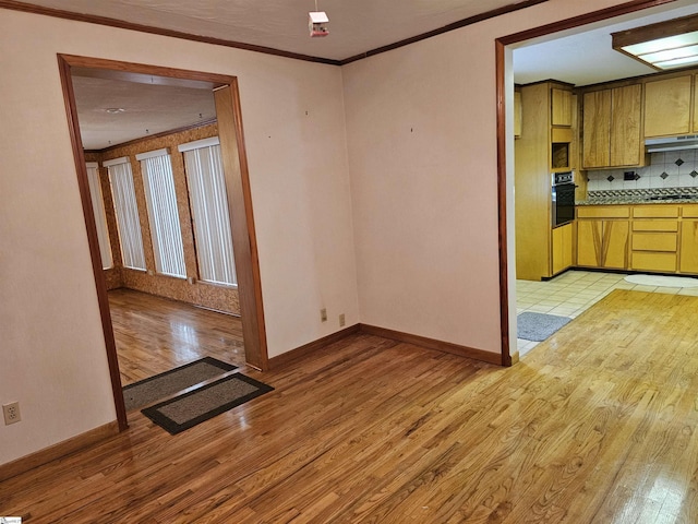 unfurnished dining area featuring visible vents, ornamental molding, light wood-style flooring, and baseboards