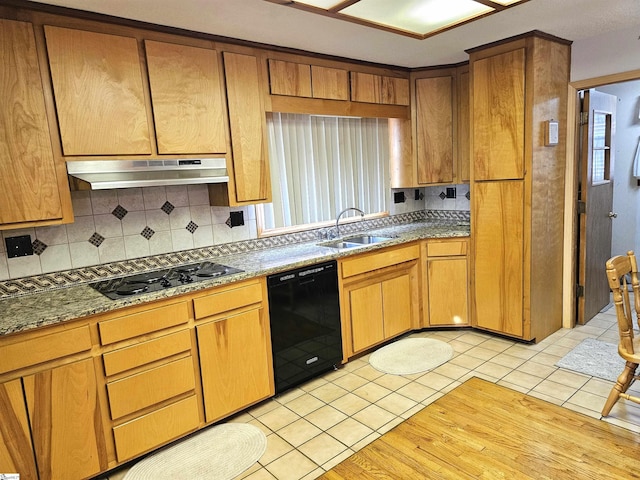 kitchen featuring tasteful backsplash, a sink, under cabinet range hood, and black appliances