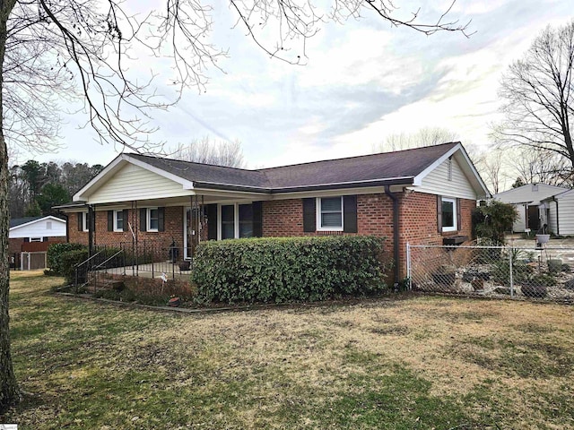 view of front of home featuring fence private yard, brick siding, and a front lawn