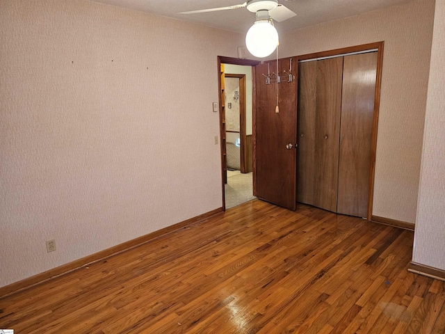 unfurnished bedroom featuring a ceiling fan, a closet, baseboards, and wood finished floors