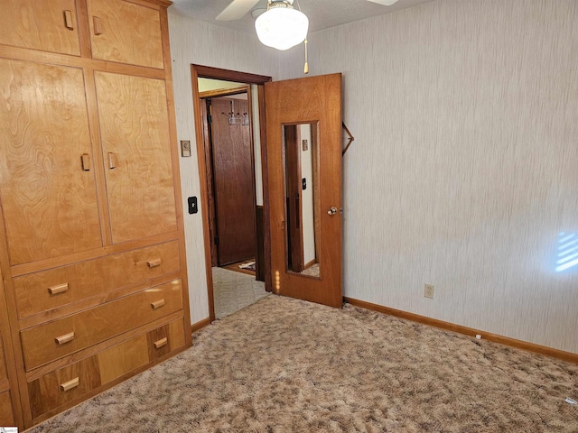 unfurnished bedroom with carpet floors, baseboards, and a ceiling fan