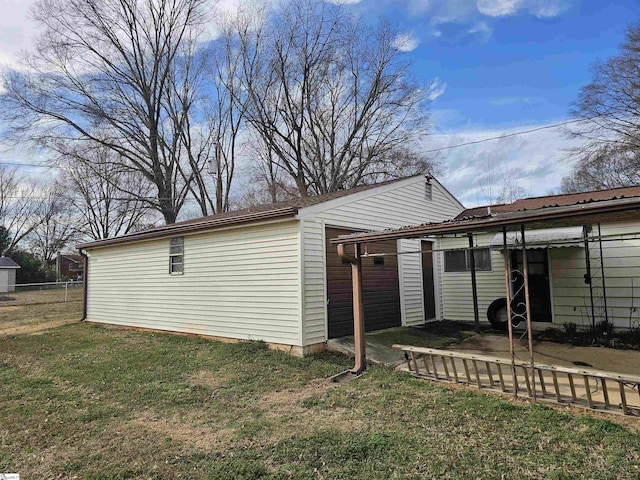 rear view of property with a garage, a lawn, and fence