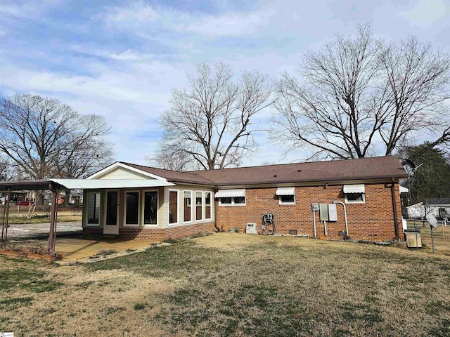 back of house featuring a lawn and brick siding