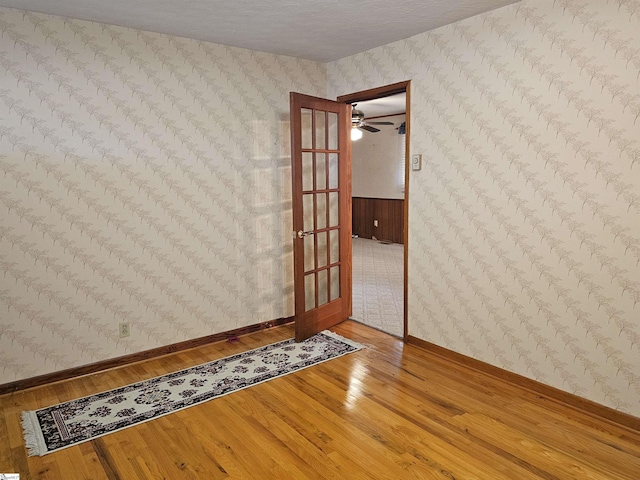 empty room with wallpapered walls, baseboards, and wood finished floors