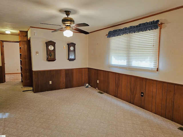 empty room featuring a wainscoted wall, wood walls, and ceiling fan