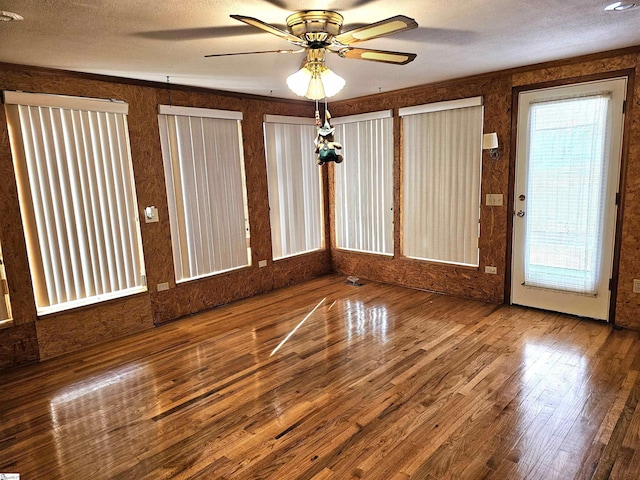 spare room featuring a textured ceiling, wood finished floors, a ceiling fan, and crown molding