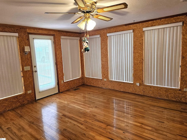 empty room featuring crown molding, a textured ceiling, and wood finished floors