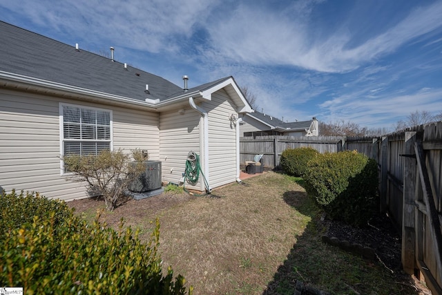 back of property featuring a fenced backyard, a yard, and central AC unit