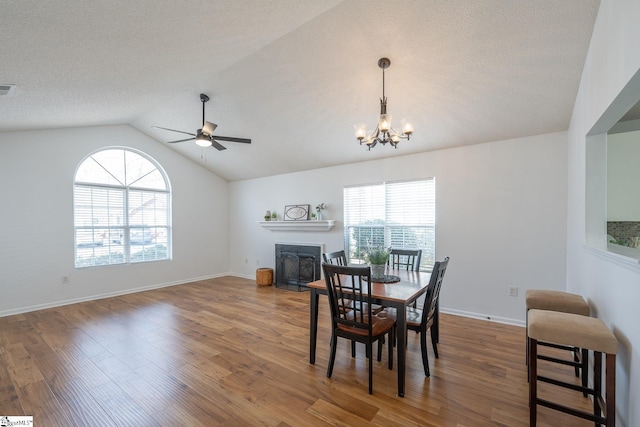 dining space with vaulted ceiling, dark wood finished floors, and ceiling fan with notable chandelier