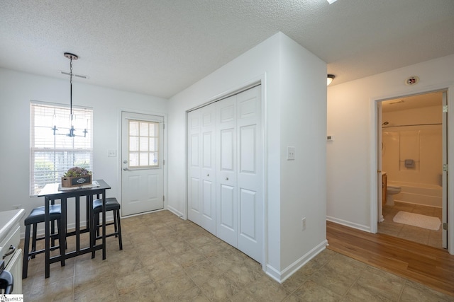 entryway with visible vents, a textured ceiling, and baseboards