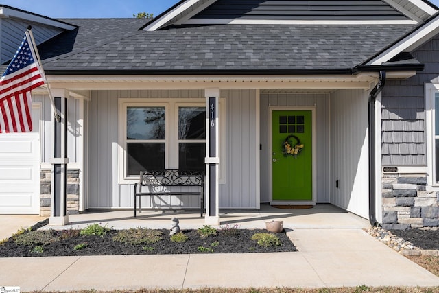 view of exterior entry featuring stone siding, covered porch, and roof with shingles