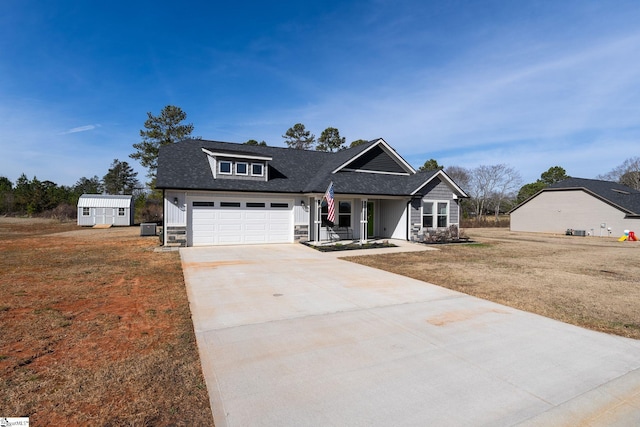 view of front of house with roof with shingles, a storage shed, a front yard, stone siding, and driveway