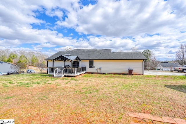 rear view of property featuring a gazebo, a wooden deck, and a lawn