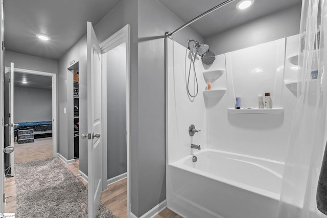 bathroom with baseboards, shower / bathing tub combination, wood finished floors, and recessed lighting