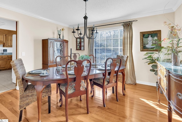 dining space with light wood finished floors, ornamental molding, a textured ceiling, and a notable chandelier