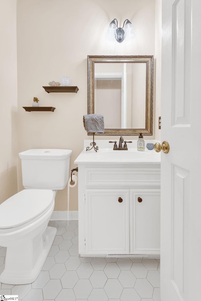 bathroom featuring toilet, tile patterned flooring, baseboards, and vanity