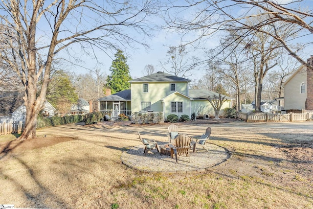 back of property with a sunroom, fence, a fire pit, and a lawn