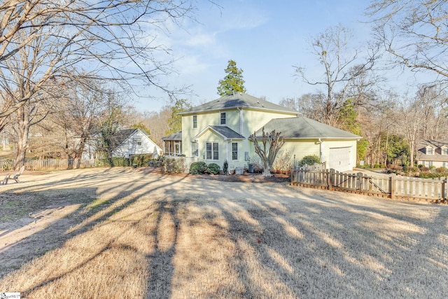 exterior space with driveway, a front lawn, an attached garage, and fence