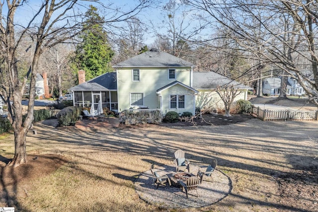 back of property with a fire pit, fence, a sunroom, a yard, and roof with shingles