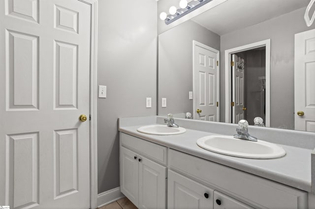 bathroom featuring double vanity, a sink, and baseboards