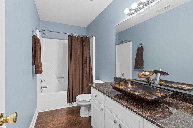 bathroom with toilet, wood finished floors, vanity, visible vents, and shower / bath combo with shower curtain