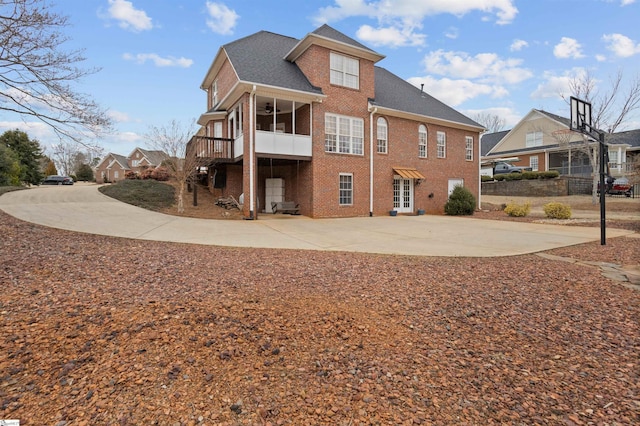 rear view of house featuring brick siding, ceiling fan, and roof with shingles