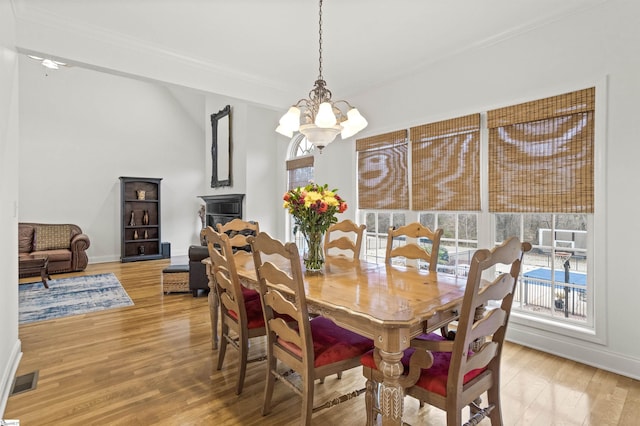 dining space with visible vents, light wood finished floors, a chandelier, and a wealth of natural light