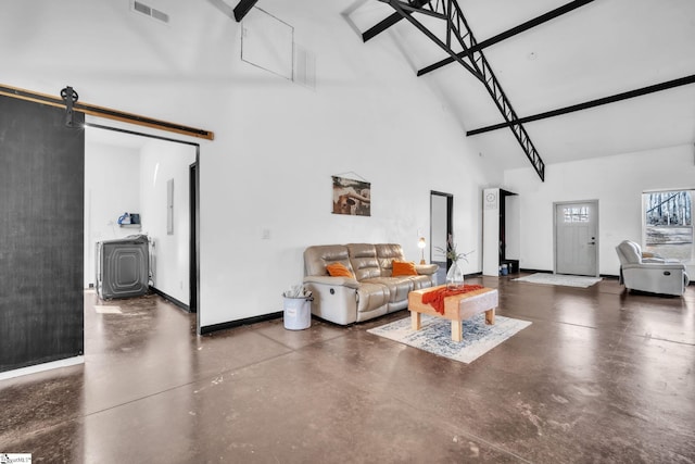 living room featuring finished concrete flooring, a barn door, visible vents, baseboards, and a towering ceiling