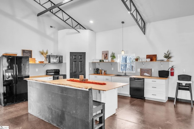 kitchen featuring finished concrete flooring, open shelves, white cabinetry, a kitchen island, and black appliances