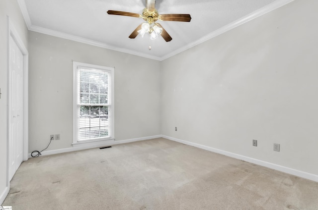 empty room with ornamental molding, light carpet, visible vents, and baseboards