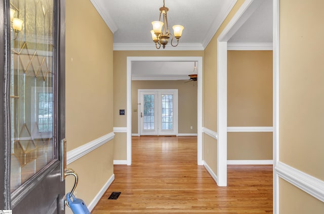 foyer entrance featuring light wood finished floors, baseboards, visible vents, and crown molding