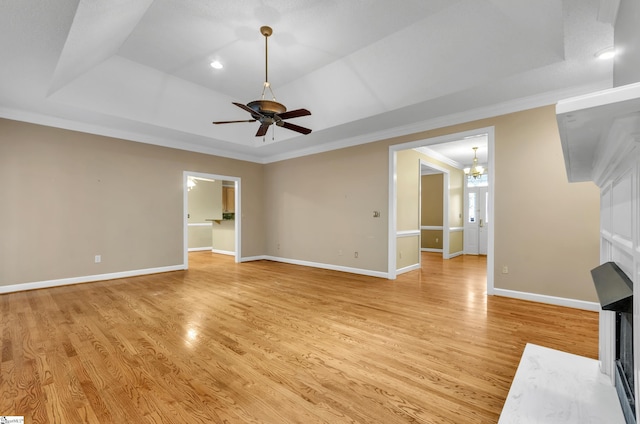 unfurnished living room featuring a raised ceiling, light wood-style flooring, and a multi sided fireplace