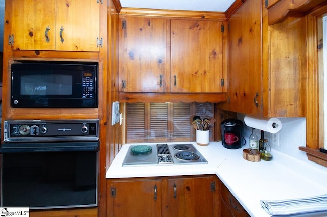 kitchen featuring brown cabinetry, light countertops, and black appliances