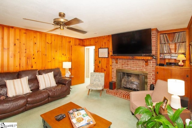 living room featuring wood walls, a brick fireplace, carpet flooring, and a ceiling fan