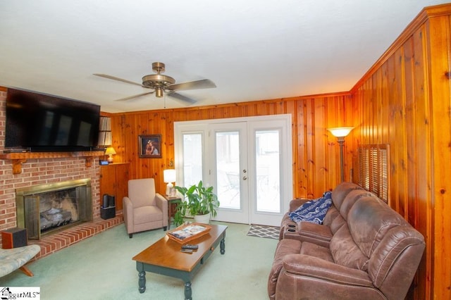 living area with carpet, french doors, wood walls, and a brick fireplace