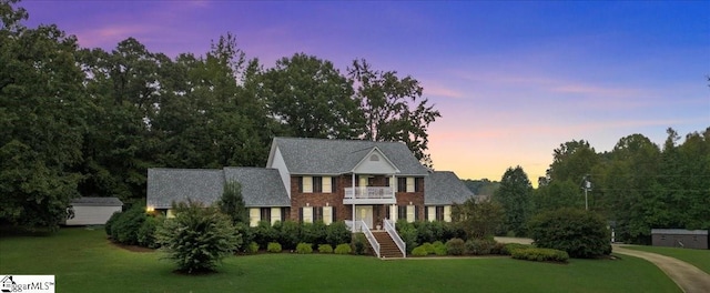 view of front facade with stairway, a lawn, and a balcony