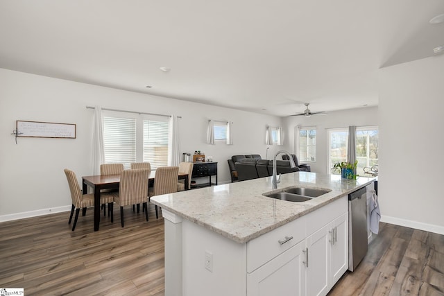 kitchen with a sink, white cabinets, open floor plan, stainless steel dishwasher, and an island with sink