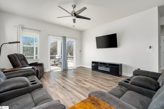 living room with light wood finished floors, baseboards, and a ceiling fan