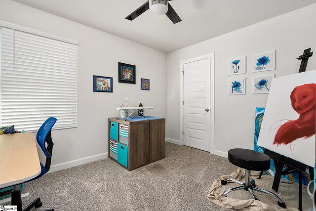 office area with a ceiling fan, light carpet, and baseboards