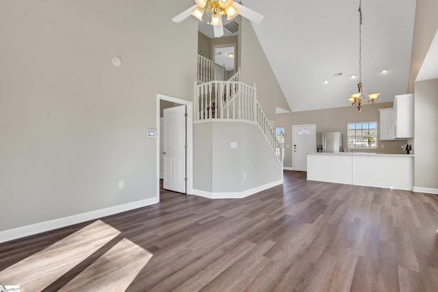 unfurnished living room featuring baseboards, visible vents, stairway, dark wood-style flooring, and ceiling fan with notable chandelier